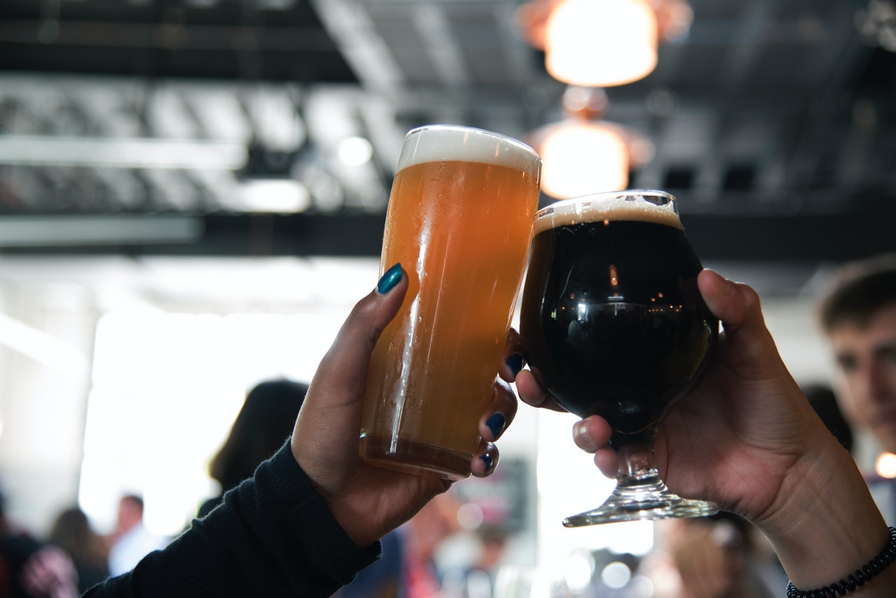 two hands toasting with a pint and a goblet